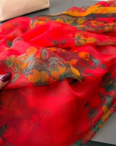 Detailed texture of red chiffon scarf with orange and leaf print on a dark surface