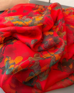 Detail of red floral scarf featuring vibrant orange flowers and light semi-transparent fabric