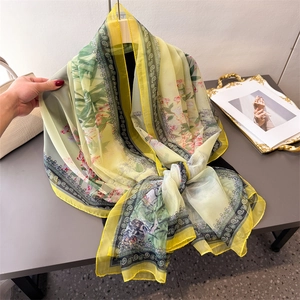 Lightweight yellow and green paisley floral chiffon scarf shown on a wooden hanger