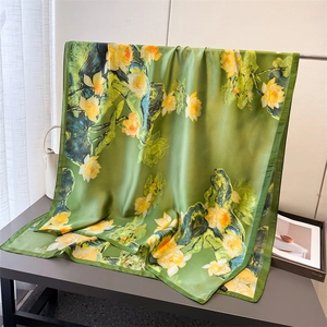 Macro shot of green silk scarf featuring golden lotus print and light floral texture