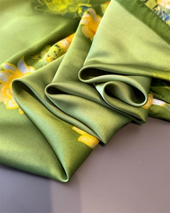 Detailed view of green floral satin scarf featuring yellow sunflower print and soft folds