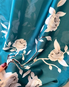 Detailed texture of dark green silk scarf with white rose floral patterns and drape