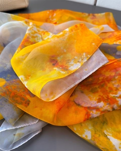Detailed macro view of vibrant orange floral silk scarf texture and semi-transparent fabric