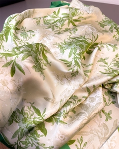 Close-up of lightweight silk-like scarf featuring green floral prints and jacquard texture