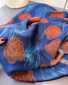 Detailed texture of silk scarf featuring orange roses on a navy blue floral background