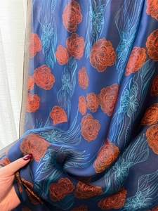 Detail of floral printed silk scarf showing soft fabric texture and orange rose patterns