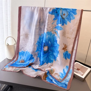 Macro detail of silk scarf featuring large blue floral prints and brown rolled edges