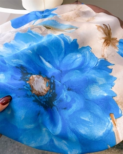 Detailed macro view of floral printed silk scarf with smooth satin texture and blue flowers