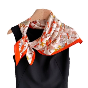 Silk-textured square scarf with orange leaf floral print on a wooden hanger