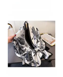 Detailed view of floral pattern and black border on a glossy silk-like scarf