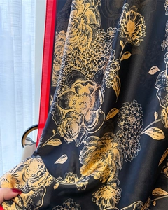 Detailed view of floral silk scarf featuring elegant gold patterns on a black base
