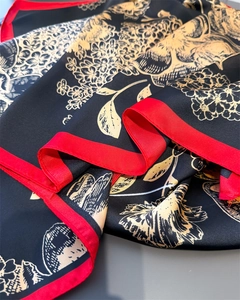 Detail of silk-like scarf with floral print on black background and red contrast hem