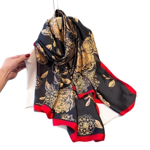Elegant silk-like floral scarf with golden peonies and red borders on black fabric