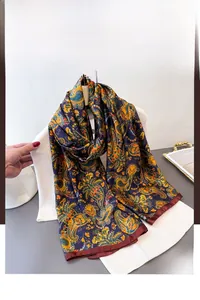 Détail de l'écharpe en soie bleu marine avec motifs paisley et bordures rouges élégantes