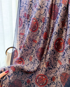 Détail d'un châle en soie paisley avec motifs d'oiseaux rouges et texture soyeuse