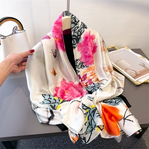 Elegant white satin scarf with rose prints and orange accents displayed on a light background