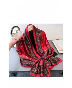 Détail d'une écharpe en soie au contraste rouge et noir avec motifs floraux dorés