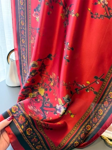Détail d'une écharpe en soie rouge montrant l'imprimé fleur de prunier et texture