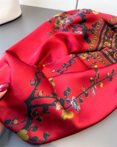 Gros plan d'une écharpe en soie rouge avec imprimé fleur de prunier noir et or lisse