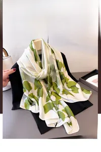 Détail d'un foulard soyeux crème avec imprimé de feuilles de ginkgo vert sur noir