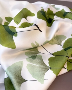 Vue détaillée d'une écharpe en soie synthétique blanche avec imprimé feuilles de ginkgo
