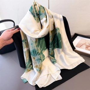 Élégant foulard en soie ivoire aux motifs de feuilles vert foncé sur un blazer noir