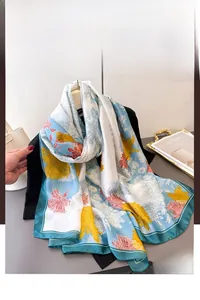 Detail of floral print silk scarf with yellow chrysanthemums and blue border on black garment