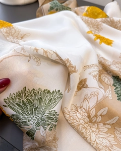 Detail of silk scarf showing smooth texture and elegant yellow chrysanthemum print