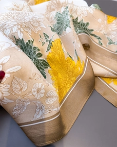Detail of silk-like satin scarf featuring elegant yellow chrysanthemum print and striped edges