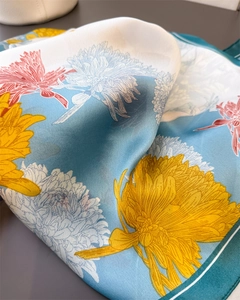 Detail of floral silk scarf with yellow chrysanthemum print and smooth satin texture