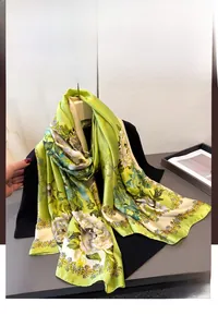 Detail of green floral silk scarf featuring white peonies and elegant golden borders