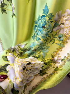 Close-up of green silk scarf showing smooth satin texture and floral peony pattern