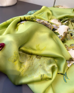 Detailed close-up of glossy green floral satin scarf showing smooth fabric drape and texture