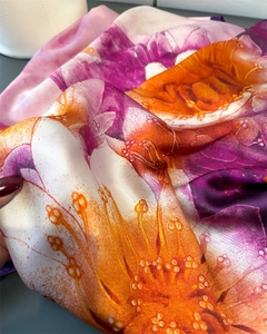 Detailed texture of silky floral scarf with orange and purple botanical prints