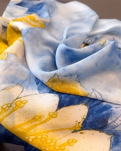 Close-up of a floral silk scarf showing vibrant blue and yellow prints with satin luster