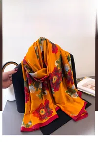Detailed texture of orange silk scarf with red peony pattern and fine edge stitching