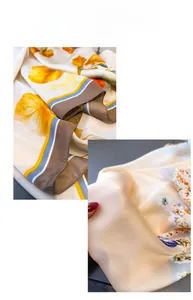 Detail of silk-like scarf with orange floral print and striped edges showing soft drape
