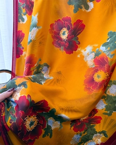 Macro shot of silk scarf showing red peonies on yellow fabric with soft texture