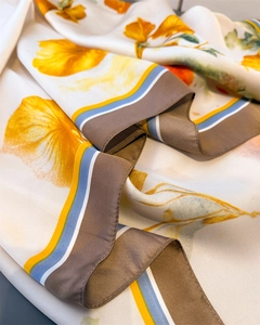 Detailed view of silk-like satin scarf featuring orange floral patterns and striped edges