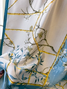 Close-up of silk-like scarf featuring yellow bamboo patterns and delicate floral prints