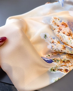 Macro shot of abstract floral print on silk satin scarf with champagne gold sheen