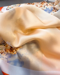 Detailed macro view of champagne silk scarf featuring vibrant floral prints and satin texture