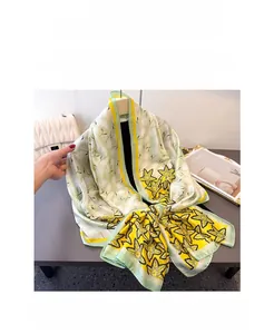 Detail of light green silk scarf featuring yellow floral patterns and smooth satin finish