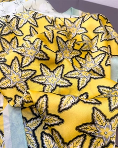 Detailed view of yellow satin scarf featuring elegant grey and white floral print texture