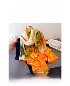 Detailed view of the soft abstract floral print silk scarf in orange and green