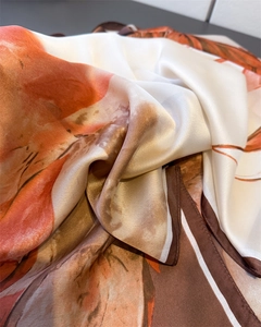 Detailed macro shot of abstract orange and brown silk scarf texture and fine edge stitching