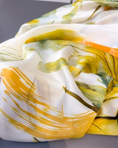 Detailed macro view of vibrant yellow and green floral silk scarf with soft draped texture