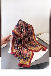 Gros plan sur une écharpe en soie bohème avec motifs ethniques bordeaux et dorés