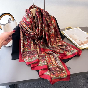 Châle en satin imprimé ethnique rouge foncé effet soie drapé sur un blazer noir