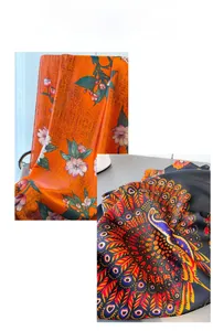 Nahaufnahme von seidigen langen Schals mit orangefarbenem Blumen- und Pfauendruck